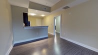 Unit 404 is a well-designed 1-bedroom, 1-bathroom residence that makes efficient use of its single-floor layout. The open-concept living and kitchen area serves as the heart of the home, featuring a peninsula-style breakfast bar that separates the kitchen from the living space while maintaining an airy, connected feel. The kitchen is equipped with full-size appliances, including a refrigerator, and offers ample counter space for everyday use. Dark hardwood-style flooring runs throughout the main living areas, adding warmth and a modern aesthetic that contrasts cleanly with the light-toned walls. Recessed and flush-mount ceiling lighting provides consistent illumination throughout. The bedroom is a generously proportioned private retreat, continuing the same hardwood-style flooring and benefiting from a calm, neutral color palette. The bathroom is conveniently situated adjacent to the bedroom, featuring a functional layout with standard fixtures. A closet with double doors provides practical storage within the unit. The overall design emphasizes clean lines, neutral tones, and a cohesive flow between spaces, making Unit 404 a comfortable and practical residence suited for everyday living.