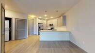 Located in Sandy Springs, GA (30328), this single-floor residence offers a thoughtfully designed layout with modern finishes throughout. The open-concept kitchen serves as the centerpiece of the living area, featuring gray shaker-style cabinetry with brushed nickel hardware, quartz countertops, a white subway tile backsplash, and a full suite of stainless steel appliances including a French door refrigerator, electric range, over-the-range microwave, and dishwasher. A peninsula with pendant lighting above provides additional counter space and defines the transition between the kitchen and the open living area. Light wood-tone flooring flows throughout the main living spaces, creating a bright and cohesive aesthetic. The bathroom is finished with gray shaker vanity cabinetry, a quartz countertop, a large framed mirror, and a soaking tub surrounded by white subway tile. A spacious walk-in closet with wire shelving and carpeted flooring offers generous storage. The bedroom is carpeted and features a large window with horizontal blinds, allowing ample natural light and views of the surrounding area. Recessed lighting and neutral wall tones throughout contribute to a clean, contemporary ambiance.