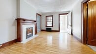 Located at 383-385 Wellington St W, this one-bedroom, one-bathroom unit offers a thoughtfully arranged single-floor layout that blends classic architectural character with practical living. The living room serves as the heart of the space, showcasing warm hardwood floors, crown moulding, rich dark wood trim, and a decorative fireplace with a classic mantel and white brick surround — a true focal point of the room. A cast iron radiator and multi-pane windows allow natural light to filter in, enhancing the unit's inviting ambiance. Elegant dark wood doors with brass hardware are found throughout, adding a cohesive vintage charm. The bedroom is a comfortable, sunlit room with hardwood flooring, neutral walls, a large window overlooking the street, and its own cast iron radiator. The kitchen features white cabinetry, white tile backsplash, stainless steel appliances including a full-size refrigerator and stove, light tile flooring, and a window for natural ventilation. A set of glass-paned French doors adds a decorative touch to the kitchen area. The bathroom is clean and functional, with subway tile surrounding the bathtub and shower, tile flooring, and classic white fixtures. Overall, the unit offers a warm, character-filled atmosphere rooted in traditional design details.