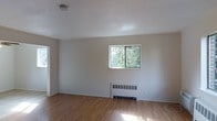 Located at 41 Wolfpit Ave in Norwalk, Connecticut, this two-floor space offers a straightforward and functional layout with a clean, neutral aesthetic. The interior is finished with warm hardwood flooring that runs throughout, complementing the bright white walls and ceilings to create an open, airy feel. Natural light filters in through windows that frame views of surrounding greenery, adding a pleasant outdoor connection to the interior environment. A wall-mounted radiator unit provides efficient heating, blending seamlessly into the understated design. The smooth white ceilings and minimal trim details give each room a clean, uncluttered character. The overall ambiance is calm and versatile, offering a blank canvas well-suited for a variety of uses. Spread across two floors, the space provides a practical separation of areas while maintaining a cohesive design language throughout. The natural light, hardwood floors, and views of mature trees outside contribute to a welcoming and comfortable atmosphere at this Norwalk address.