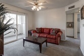 Located at 23402 Hemlock Ave in Moreno Valley, California, this single-floor residence offers a well-organized layout with comfortable living spaces throughout. The living room serves as the heart of the home, featuring plush carpeting, crown molding, a ceiling fan with integrated lighting, and a sliding glass door that opens to a private balcony with views of surrounding greenery. A built-in shelving nook adds a functional architectural detail to the space.

The kitchen is efficiently designed in an L-shaped configuration, outfitted with ample white cabinetry accented by warm wood trim, light granite-style countertops, tile flooring, and a full suite of white appliances including a refrigerator, electric range, dishwasher, and sink.

The residence includes multiple bedrooms, each carpeted and filled with natural light from generously sized windows. The bedrooms offer comfortable proportions and a calm, neutral ambiance well-suited for rest.

The bathroom features tile flooring, a well-lit vanity with a large mirror, under-sink cabinetry, and a shower-tub combination. Throughout the home, a consistent neutral color palette and practical finishes contribute to a clean, cohesive aesthetic.