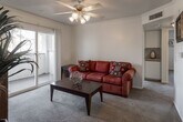 Located at 23402 Hemlock Ave in Moreno Valley, California, this single-floor residence offers a well-organized layout with comfortable living spaces throughout. The living room serves as the heart of the home, featuring plush carpeting, crown molding, a ceiling fan with integrated lighting, and a sliding glass door that opens to a private balcony with views of surrounding greenery. A built-in shelving nook adds a functional architectural detail to the space.

The kitchen is efficiently designed in an L-shaped configuration, outfitted with ample white cabinetry accented by warm wood trim, light granite-style countertops, tile flooring, and a full suite of white appliances including a refrigerator, electric range, dishwasher, and sink.

The residence includes multiple bedrooms, each carpeted and filled with natural light from generously sized windows. The bedrooms offer comfortable proportions and a calm, neutral ambiance well-suited for rest.

The bathroom features tile flooring, a well-lit vanity with a large mirror, under-sink cabinetry, and a shower-tub combination. Throughout the home, a consistent neutral color palette and practical finishes contribute to a clean, cohesive aesthetic.