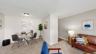 Located at 2419 Wycliffe Rd in Raleigh, NC, this single-floor residence offers a well-organized layout designed for comfortable everyday living. The living area is an inviting, open space finished with plush carpeting and neutral-toned walls, bathed in natural light through large floor-to-ceiling windows and sliding glass doors that open to an outdoor brick-accented patio area. The room provides ample space for multiple seating arrangements and a dining area, making it equally suited for relaxing and entertaining. A secondary sitting area or flex room offers additional versatile living space, also carpeted and naturally lit. The kitchen features white cabinetry, black appliances including a full-size refrigerator and electric range, a single-basin sink, and wood-look flooring, offering a clean and functional workspace. The bedrooms are carpeted and serene, with the primary bedroom showcasing a generous walk-in closet and a window that brings in soft natural light. The bathroom includes classic white tile wainscoting, providing a clean and timeless aesthetic. Throughout the residence, textured ceilings, consistent neutral tones, and thoughtful transitions between carpeted and hard-surface flooring create a cohesive and comfortable atmosphere.