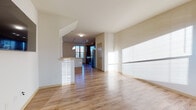 This two-story residence at 1525 Wisconsin Ave in Grafton, Wisconsin, offers a thoughtfully designed layout spread across two floors. The main living area is open and airy, with light hardwood-style flooring that runs continuously through the living and dining spaces, reflecting abundant natural light that streams in through multiple windows. A half-wall with a breakfast bar connects the living area to the kitchen, creating a seamless flow between spaces.

The kitchen is a standout feature, showcasing rich dark-wood cabinetry, granite countertops, and a large central island with a sink. Stainless steel appliances — including a refrigerator, range, and microwave — complement the modern aesthetic, while pendant lighting and track fixtures illuminate the workspace. A wide window brings in additional natural light, enhancing the kitchen's welcoming atmosphere.

The bedroom is generously proportioned, featuring plush carpeting and a ceiling fan. Two bathrooms serve the residence: a full bath with a walk-in glass-door shower, dark-wood vanity, and light countertop, and a half bath with matching vanity finishes. The stairwell connecting the two floors features clean architectural lines, contributing to the residence's modern, neutral aesthetic throughout.