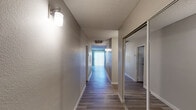 This single-story residence showcases a thoughtfully designed layout with consistent, contemporary finishes throughout. The flooring is a standout feature, with durable wood-look laminate planks running continuously across the living areas, bedrooms, kitchen, and hallways, contributing to a cohesive and modern aesthetic.

The living room is generously proportioned, anchored by a clean-lined fireplace with a white surround and complemented by a ceiling fan with integrated lighting. Vertical blinds on the windows allow for adjustable natural light, enhancing the room's open and airy feel.

The kitchen is well-equipped with crisp white shaker-style cabinetry, gray quartz countertops, a stainless steel sink, and a classic white subway tile backsplash. A bright window above the counter area fills the space with natural light, while the wood-look flooring continues seamlessly from the rest of the home.

A long interior hallway connects the main living spaces to the bedrooms, lined with wall sconce lighting and featuring mirrored sliding closet doors. Each bedroom is comfortably sized, finished with the same laminate flooring, ceiling fans, and windows fitted with horizontal blinds that invite ample daylight. The neutral wall tones and textured ceilings are consistent throughout, creating a calm and functional living environment.