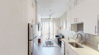 Located in the heart of Austin's dynamic East 6th Street neighborhood, this efficiently designed two-bedroom, one-bathroom unit offers a clean, contemporary aesthetic across a single floor. The living room sets a welcoming tone with soft sage-green walls, light wood-style flooring, a ceiling fan, and a large vertical-blind window that draws in generous natural light — creating a bright, airy atmosphere. Framed artwork adds a curated touch throughout the space.

The galley-style kitchen is a standout feature, lined with floor-to-ceiling white cabinetry offering ample storage, complemented by sleek stainless steel appliances including a refrigerator, electric range, and microwave. Light countertops and wood-tone flooring maintain a cohesive, modern feel.

Both bedrooms are compact yet functional, dressed in the same calming sage palette with light wood flooring. The primary bedroom benefits from natural light through slatted blinds, while the second bedroom offers a cozy, minimalist retreat.

The bathroom is finished in a crisp, all-white scheme featuring a shower-tub combination with tile surround, a single-sink vanity with white cabinetry, and wood-look flooring — balancing practicality with clean design. The overall unit presents a well-appointed, turnkey space ideal for urban living in one of Austin's most sought-after neighborhoods.