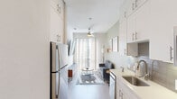 Located in the heart of Austin's dynamic East 6th Street neighborhood, this efficiently designed two-bedroom, one-bathroom unit offers a clean, contemporary aesthetic across a single floor. The living room sets a welcoming tone with soft sage-green walls, light wood-style flooring, a ceiling fan, and a large vertical-blind window that draws in generous natural light — creating a bright, airy atmosphere. Framed artwork adds a curated touch throughout the space.

The galley-style kitchen is a standout feature, lined with floor-to-ceiling white cabinetry offering ample storage, complemented by sleek stainless steel appliances including a refrigerator, electric range, and microwave. Light countertops and wood-tone flooring maintain a cohesive, modern feel.

Both bedrooms are compact yet functional, dressed in the same calming sage palette with light wood flooring. The primary bedroom benefits from natural light through slatted blinds, while the second bedroom offers a cozy, minimalist retreat.

The bathroom is finished in a crisp, all-white scheme featuring a shower-tub combination with tile surround, a single-sink vanity with white cabinetry, and wood-look flooring — balancing practicality with clean design. The overall unit presents a well-appointed, turnkey space ideal for urban living in one of Austin's most sought-after neighborhoods.