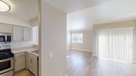 This single-floor residence offers a thoughtfully designed layout that balances comfort and functionality. The open-concept living and dining area is anchored by warm hardwood-style flooring, neutral-toned walls, and crown molding that adds a refined architectural touch. Vaulted ceilings in the living space lend an airy, expansive feel, while large windows and a sliding glass door with vertical blinds allow generous natural light to fill the room throughout the day.

The kitchen is well-equipped with stainless steel appliances, including a gas range, over-the-range microwave, refrigerator, and dishwasher. Taupe cabinetry pairs with speckled granite-style countertops, providing ample storage and prep space. A pass-through counter connects the kitchen to the living area, enhancing the open flow of the home.

The bedroom features plush carpeting, a ceiling fan with light fixture, and a pair of windows that overlook the outdoors. A reach-in closet provides convenient storage. Adjacent to the bedroom is a dedicated in-unit laundry area with a stacked washer and dryer.

The bathroom is finished with matching granite-style countertops, taupe cabinetry, and light tile flooring, maintaining a cohesive aesthetic throughout. Clean lines and neutral tones create a calm, move-in-ready environment.