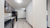 Located at 1267 11th Ave SW in Forest Lake, MN, this one-bedroom, one-bathroom unit offers a practical and comfortable single-floor layout. Light-toned vinyl plank flooring runs throughout the main living areas, complementing the clean white walls and dark baseboards that give the space a modern, cohesive look.

The kitchen is efficiently designed and features dark cabinetry, granite-look countertops, a double-basin stainless steel sink, and black appliances including a full-size refrigerator and electric range. A textured ceiling adds subtle character to the kitchen area.

The living room is open and bright, with a window unit air conditioner and baseboard heating, ensuring year-round comfort. A window allows natural light to filter in, offering views of the surrounding neighborhood.

The bedroom is a generously sized retreat finished with plush carpet, a ceiling fan with integrated lighting, a window for natural light, and a sliding-door closet offering ample storage. Baseboard heating ensures warmth throughout the cooler Minnesota months.

The bathroom is clean and well-lit, featuring a granite-top vanity, a lighted mirror, a tub-shower combination, and vinyl plank flooring. A connecting hallway ties all rooms together, creating a logical and efficient flow throughout the unit.