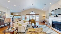 Located at 346 Shadow Creek Ln in Anderson, South Carolina, this single-floor space offers a thoughtfully designed open-plan layout that seamlessly connects the living and dining areas. The most striking architectural feature is the soaring vaulted ceiling, which amplifies the sense of openness and volume throughout the main living area. A ceiling fan is centrally mounted, adding both function and visual interest beneath the high roofline.

Warm hardwood floors run throughout the space, providing a cohesive foundation that complements the neutral, cream-toned walls. Large windows adorned with decorative valances flood the interior with natural light and offer views of the surrounding neighborhood. An arched transom window adds a refined architectural touch near the entryway.

The living area is anchored by a classic white-tiled fireplace with a mantel, which serves as a natural focal point. Multiple seating arrangements allow for versatile use of the space. The adjacent dining area features direct access to the outdoors through a glass-paneled door, further enhancing the connection between interior and exterior.

A kitchen with bar-height seating and standard appliances is visible from the dining zone, reinforcing the open and interconnected nature of the floor plan. Recessed lighting complements the natural light throughout. Overall, the space presents a warm, welcoming ambiance with clean lines and bright, airy interiors.