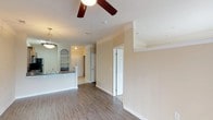 Located at 3801 Glen Verde Trl in Raleigh, NC, this single-floor residence offers a well-designed open-concept layout with a warm, neutral color palette throughout. The living area is spacious and bright, featuring hardwood-style flooring, crown molding, and a ceiling fan with a light fixture. A sliding glass door floods the room with natural light and provides access to a private balcony with outdoor views, enhancing the overall sense of openness.

The kitchen is thoughtfully designed with warm-toned wood cabinetry, dark granite-style countertops, and stainless steel appliances including a refrigerator, electric range, and built-in microwave. A peninsula counter with pendant lighting separates the kitchen from the dining area, creating a functional and inviting space for cooking and entertaining. Built-in arched shelving adds a charming architectural detail nearby.

The bathroom is well-appointed, featuring dark wood cabinetry with matching countertops, a full bathtub, and hardwood-style flooring. An adjacent walk-in closet provides generous storage. The bedroom connects directly to the bathroom and balcony, offering a comfortable and private retreat. Carpet flooring in the bedroom adds warmth and comfort. Crown molding and consistent finishes throughout give the space a cohesive and polished feel.