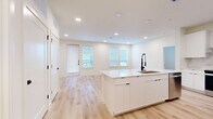 This thoughtfully designed 2-bedroom, 3-bathroom home in Round Rock, Texas offers a clean, modern aesthetic throughout its well-utilized single-floor layout. Light wood flooring flows seamlessly across every room, complementing the crisp white walls and recessed lighting that keep the space bright and airy.

The open-concept kitchen and living area serves as the heart of the home. The kitchen is outfitted with flat-front white cabinetry, a marble-style tile backsplash, stainless steel appliances including a range, built-in microwave, and refrigerator, as well as a sleek wall-mounted range hood. A large central island with a white quartz countertop and matte black fixtures provides additional prep space and casual seating. Multiple windows and a glass-panel door in the living area invite abundant natural light and offer outdoor views.

The spacious primary bedroom features multiple windows that fill the room with daylight, while the second bedroom is equally well-lit with its own window and ceiling fan. The primary bathroom is notably refined, showcasing a dual-sink vanity with quartz countertops, LED-backlit mirrors, matte black hardware, and a glass-enclosed walk-in shower with large-format tile. The additional bathrooms maintain the same high-quality, contemporary finishes found throughout the home.