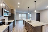 Located at 3401 E Washington Ave in Madison, WI, this well-appointed 3-bedroom, 2-bathroom unit offers a thoughtfully designed single-floor layout. The open-concept living, dining, and kitchen area serves as the heart of the home, featuring wood-look plank flooring, recessed and pendant lighting, and large windows that fill the space with natural light. The kitchen is equipped with stainless steel appliances, rich dark cabinetry, a white subway tile backsplash, and a generously sized granite island with a double sink — ideal for both cooking and entertaining. The living area extends to a private balcony through sliding glass doors, providing outdoor views of the surrounding Madison cityscape. Each of the three bedrooms offers plush carpeting, ceiling fans, and ample natural light, with the primary bedroom featuring a comfortable footprint. Six closets throughout the unit, including walk-in options with wire shelving systems, provide exceptional storage. The two bathrooms are finished with granite-topped vanities and dark cabinetry. A dedicated laundry area and a welcoming entrance complete this modern, well-equipped unit designed for comfortable urban living.