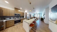 This contemporary single-floor residence showcases a thoughtfully designed open-concept layout that seamlessly connects the kitchen, dining, and living areas. The kitchen is a standout feature, outfitted with sleek flat-front wood cabinetry, granite countertops, and a full suite of stainless steel appliances including a range, microwave, dishwasher, and French door refrigerator. A spacious island with seating provides an ideal casual dining and gathering space, accented by modern pendant lighting overhead. Light wood-style flooring flows throughout the main living areas, enhancing the bright, airy atmosphere. The living room offers a comfortable, open setting with ample natural light and room for relaxed entertaining. Multiple bedrooms are well-proportioned and carpeted, each featuring large windows that invite natural light and views of the surrounding area, along with ceiling fans for added comfort. The primary bathroom impresses with a double-sink granite vanity, wood cabinetry, and direct access to the primary bedroom. Secondary bathrooms mirror the same quality finishes, featuring single granite vanities and clean, modern fixtures. Throughout the residence, a cohesive neutral palette, recessed lighting, and consistent high-quality materials create a polished, contemporary living environment.