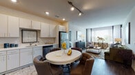 Located at 11001 W 15th Pl in Lakewood, Colorado, this single-floor residence offers a thoughtfully designed open-concept layout that seamlessly connects the kitchen, dining, and living areas. The kitchen is equipped with stainless steel appliances — including a refrigerator, dishwasher, microwave, and range — complemented by white cabinetry with sleek hardware and light countertops. Wood-look flooring runs throughout the main living areas, adding warmth and continuity. The dining area accommodates a round table with upholstered chairs, positioned directly adjacent to the kitchen for convenient everyday use. The living room is bathed in natural light from large windows with blinds and draping curtains, creating a bright and welcoming atmosphere. The bedroom features plush carpeting, generous windows, and ample space for a full bedroom suite. Two bathrooms serve the residence: one with a vanity and wood-look flooring, and a second en-suite bathroom with a glass-enclosed shower, dual vanity, and direct access to the bedroom. Recessed and track lighting throughout provide effective illumination. The overall design is neutral and modern, offering a clean, comfortable living environment in the heart of Lakewood.