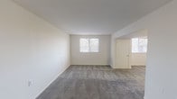This single-floor unit offers a straightforward and functional layout, as illustrated by the 3D floor plan, which reveals a well-organized arrangement of living, sleeping, kitchen, and bathroom spaces. The living area is generously sized, featuring neutral cream-toned walls, grey wall-to-wall carpeting, and multiple windows fitted with horizontal blinds that allow natural light to fill the room. An open passage connects the living area to additional carpeted spaces, maintaining a cohesive flow throughout.

The kitchen is equipped with warm wood-toned cabinetry, light laminate countertops, a double-coil electric range, a full-size white refrigerator, and a single-basin sink. Light hardwood-style flooring and overhead fluorescent lighting give the kitchen a practical, clean appearance.

Multiple bedrooms are present, each finished with the same grey carpeting and cream walls found in the living area. Each bedroom includes at least one window with blinds, providing natural light and exterior views.

Two full bathrooms serve the unit, both featuring hardwood-style flooring, white vanities with mirrored medicine cabinets, a toilet, and a bathtub/shower combination. The clean white palette and efficient use of space make both bathrooms functional and well-maintained. Overall, the unit presents a clean, neutral aesthetic suitable for a variety of residents.