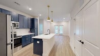 Located at 900 Corby Lane in Charleston, SC, this well-appointed 2-bedroom, 2-bathroom residence offers a thoughtfully designed single-level layout with a cohesive modern aesthetic. Light hardwood flooring flows seamlessly throughout the entire space, creating a bright, airy atmosphere complemented by recessed lighting and large windows.

The open-concept kitchen and living area serves as the heart of the home. The kitchen is a standout, featuring bold navy shaker-style cabinetry with gold hardware, a classic white subway tile backsplash, crisp white quartz countertops, and stainless steel appliances. A central island with a matte black gooseneck faucet and pendant lighting above provides additional prep space and casual seating. The adjacent living area opens directly to a private balcony via French doors, filling the space with natural light.

Both bedrooms are comfortably sized, with the primary bedroom offering a ceiling fan, ample natural light, and access to a dedicated closet with built-in wire shelving systems. The second bedroom also features natural light and a walk-in closet.

The bathrooms echo the navy and gold design language of the kitchen, showcasing navy vanities with white countertops, matte black fixtures, framed mirrors, and fully tiled soaking tub/shower combinations, delivering a polished, consistent finish throughout.