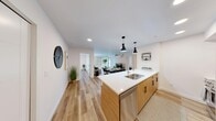 Located in Calgary, AB, this thoughtfully designed 4-bedroom, 2-bathroom unit offers a modern, open-concept layout finished with consistent light wood laminate flooring and a clean, neutral palette throughout. The combined kitchen and living area serves as the heart of the home, anchored by a large island with a white quartz countertop, double stainless steel sink, and warm wood cabinetry. Stainless steel appliances, ample upper and lower storage, and stylish black pendant lights complete the kitchen. A breakfast bar with seating connects the kitchen to a dedicated dining area, while the living room benefits from a large window with zebra blinds that allow natural light to filter in, alongside a private exterior door. The four bedrooms are well-proportioned and share consistent finishes, each featuring light wood flooring, zebra roller blinds on generous windows, and clean white walls. The primary bedroom offers a comfortable layout with access to a Jack-and-Jill style bathroom featuring a wood-toned vanity with a white basin and large mirror. The second bathroom is efficiently laid out with a shower-tub combo, matching vanity, and recessed lighting. The overall ambiance is bright, clean, and contemporary, making this a highly functional and stylish living space.