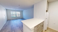 Located at Providence Village Drive in Sterling, Virginia, this two-bedroom, two-bathroom residence offers a well-designed single-floor layout filled with natural light and contemporary finishes. The open-concept living, dining, and kitchen area serves as the heart of the home, where light wood-style plank flooring flows seamlessly throughout. The kitchen features a white quartz peninsula countertop, gray shaker-style cabinetry with brushed nickel hardware, and an efficient layout that connects directly to the dining and living spaces. Large windows in the living area frame outdoor views and fill the space with natural light.

Both bedrooms are comfortably sized with the same light flooring, neutral wall tones, and windows that allow for ample daylight. The primary bedroom includes a closet, while additional closet storage is available throughout the unit. The two bathrooms are finished with coordinating gray cabinetry, white quartz countertops, and brushed nickel fixtures. One bathroom features a tub/shower combination with safety grab bars, while the other includes a walk-in shower with a grab bar and a well-lit vanity mirror. A hallway connects the private areas of the home, completing a practical and cohesive floor plan suited for comfortable everyday living.