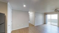 This single-floor residence offers a bright and functional layout designed with simplicity and comfort in mind. The main living area sets a welcoming tone with light-toned hardwood flooring that extends throughout, providing a cohesive and easy-to-maintain surface underfoot. Smooth, neutral-colored walls are complemented by crisp white crown molding and clean white baseboards, lending the space a polished, classic finish.

Recessed lighting in the ceiling ensures even, ambient illumination across the room, while the clean white ceiling itself contributes to an open, airy atmosphere. A set of paneled doors — likely a closet — provides practical storage directly off the main living area, adding to the unit's functionality. A thermostat is mounted on the wall, indicating climate control for year-round comfort.

The overall aesthetic is neutral and move-in ready, offering a blank canvas that suits a variety of interior styles. The straightforward, uncluttered design of the space prioritizes livability and ease of use, making it well-suited for those seeking a clean, low-maintenance living environment. The consistent use of light tones throughout creates a sense of openness and continuity across the floor plan.
