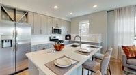 This single-floor residence offers a refined living experience through a thoughtfully designed open-concept layout with consistent, contemporary finishes throughout. The living room serves as a central highlight, featuring large windows on multiple walls that frame impressive waterfront and cityscape views, flooding the space with natural light and creating an airy, inviting atmosphere.

The kitchen is well-equipped with stainless steel appliances, including a full-size refrigerator, gas range, and microwave. Sleek gray cabinetry reaches to the ceiling for ample storage, while a generous island with white quartz countertops provides seating and additional workspace — ideal for both cooking and casual dining.

Multiple bedrooms are present, each with its own character. One bedroom features a dramatic black four-poster canopy bed frame, a walk-in closet, and an en-suite bathroom. Another bedroom offers a serene, light-filled retreat with elegant wall art and large windows overlooking neighboring architecture. A third bedroom maintains a clean, minimalist aesthetic with hardwood-style flooring and a bright window with layered window treatments.

The bathroom is clean and functional, featuring wood-look tile flooring, a tub-shower combination, a vanity with a well-lit mirror, and gray cabinetry. Hardwood-style flooring runs throughout the main living areas, tying the design together cohesively.