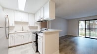 Located at 2125 Westinghouse St in San Diego, California, this single-floor residence offers a thoughtfully designed layout with modern finishes throughout. The updated kitchen is a standout feature, showcasing white shaker cabinetry, light stone countertops, a stainless steel refrigerator, and a range with an overhead ventilation hood. A skylight adds natural brightness to the space, while a peninsula counter creates a seamless transition into the open living area. The living room is bright and airy, featuring light wood-style flooring, a ceiling fan, and neutral walls that create a clean, welcoming atmosphere. Sliding glass doors lead to a private balcony with iron railings, offering views of lush landscaping and mature trees in the surrounding courtyard. The bedrooms are finished with plush carpeting and include closets, with windows that invite natural light. One bedroom features direct access to a bathroom. The bathrooms are clean and contemporary, featuring white vanities with stone countertops, brushed nickel fixtures, and framed mirrors. A secondary bathroom offers a similarly crisp, minimalist design with light wood-style flooring. The overall aesthetic is neutral and modern, making this a well-appointed space in a desirable San Diego location.
