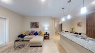 This single-floor residence offers a thoughtfully designed open-concept layout that seamlessly connects the living, dining, and kitchen areas. Light hardwood flooring flows throughout the space, contributing to a bright and cohesive aesthetic. The living room is generously sized, featuring a sliding glass door that allows natural light to fill the room and provides access to the outdoors. The kitchen is outfitted with rich, dark wood cabinetry, granite countertops, stainless steel appliances, and a breakfast bar with stylish pendant lighting overhead. A cozy dining nook adjacent to the kitchen comfortably accommodates a round dining table. The primary bedroom is a serene retreat with ample space, a ceiling fan, and an en-suite bathroom featuring granite countertops, a soaking tub with tiled surround, and a walk-in closet with built-in shelving. The second bedroom is equally comfortable, with natural light from a window and hardwood flooring. A second full bathroom with a granite vanity serves the rest of the unit. Near the entryway, a dedicated in-unit laundry area adds everyday convenience. Neutral tones throughout create a warm, inviting atmosphere well-suited to modern living.