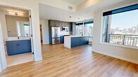 Unit 1101 at 855 N. Broadway is a modern 2-bedroom, 2-bathroom high-rise condominium spanning 910 square feet in Denver, CO. The open-concept kitchen and living area serves as the heart of the unit, featuring gray shaker cabinetry, stainless steel appliances, a white quartz waterfall island with an undermount sink, and sleek pendant lighting. Large floor-to-ceiling windows flood the space with natural light and frame sweeping views of the Denver skyline. Light-toned hardwood flooring runs throughout the entire unit, lending warmth and continuity. The primary bedroom measures 140 square feet and includes a ceiling fan and dedicated closet. The second bedroom is equally bright, featuring oversized windows with panoramic city views and an exposed concrete structural column that adds an industrial character. Both bathrooms are finished with large-format tile flooring, white subway-tiled tub-shower surrounds, gray vanities with white countertops, and matte black fixtures and hardware. Each bedroom is paired with its own closet, providing ample storage. The unit's elevated position on the 11th floor ensures breathtaking views of the Denver cityscape from multiple rooms, making this a compelling urban residence.