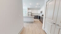 Located at 10001 Birchcrest St in Apex, NC, this 1-bedroom, 1-bathroom unit offers a thoughtfully designed layout that maximizes functionality and comfort. Light wood-style flooring runs throughout the main living areas, creating a bright and cohesive aesthetic.

The open-concept kitchen and living room serve as the heart of the unit. The kitchen is a standout feature, boasting two-tone cabinetry with white upper cabinets and slate-gray lower cabinets, granite countertops, a center island with a built-in sink, and a full suite of stainless steel appliances including a refrigerator, electric range, and over-the-range microwave. Recessed lighting illuminates the space effectively.

The living area is bright and airy, benefiting from multiple windows dressed with horizontal blinds, a ceiling fan, and direct access to the outdoors via a glass-paneled door, allowing ample natural light to filter in.

The bedroom is a comfortable, well-sized retreat featuring plush carpeting, generous natural light from dual windows, and a ceiling fan. A dedicated closet provides practical storage.

The bathroom features a clean, modern design with a combination tub and shower enclosed by white subway tile, chrome fixtures, and light wood-style flooring that complements the rest of the unit.