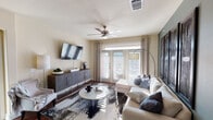 Located at 2416 Fort Worth Ave in Dallas, TX, this single-floor residence offers a thoughtfully designed layout with modern finishes and a warm, contemporary aesthetic throughout. The living room is a bright, welcoming space featuring rich hardwood-style flooring, a ceiling fan, and large French doors that invite abundant natural light while providing access to the outdoors. A wall-mounted flat-screen TV, a sleek media console, and a comfortable sectional sofa anchor the room, complemented by an elegant arc floor lamp and a patterned area rug. The kitchen is equipped with dark espresso cabinetry, white countertops, a subway tile backsplash, and stainless steel appliances including a microwave, range, and refrigerator. A central island with bar seating connects seamlessly to the dining area, which is highlighted by a striking orb chandelier and a glass-top dining table. The bedrooms are serene and comfortable, each featuring ceiling fans, carpet flooring, and ample natural light. One bedroom showcases a bold teal accent wall with a glass-top desk, adding a stylish, functional touch. Both bathrooms are well-appointed with dark cabinetry, white countertops, hardwood-style flooring, and convenient walk-in closet access—one featuring a shower-tub combination.