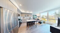 Located at 3665 Stone Way N in Seattle's vibrant Wallingford neighborhood, this thoughtfully designed one-bedroom, one-bathroom residence offers a modern and efficient layout with high-quality finishes throughout. Light-toned hardwood-style flooring flows seamlessly across the entire space, contributing to a cohesive and airy aesthetic.

The open-concept kitchen and living area serves as the heart of the home. The kitchen is equipped with stainless steel appliances, including a gas range, refrigerator, and over-the-range microwave. Light wood flat-front cabinetry, white quartz countertops, a subway tile backsplash, and a stainless steel undermount sink complete the polished look. A central island with a marble-look countertop and bar seating provides additional workspace and casual dining. The living area benefits from a large floor-to-ceiling window that floods the space with natural light and frames treetop views of the surrounding Seattle landscape.

A well-lit hallway connects the main living area to the private bedroom, dedicated closet, and bathroom. The bedroom is a calm, intimate retreat with clean white walls. The full bathroom features a wide vanity with white countertop and light wood cabinetry, a large mirror, and a soaking tub with textured tile surround. In-unit stacked laundry is also included, adding everyday convenience to this well-appointed residence.