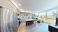 Located at 3665 Stone Way N in Seattle's vibrant Wallingford neighborhood, this thoughtfully designed one-bedroom, one-bathroom residence offers a modern and efficient layout with high-quality finishes throughout. Light-toned hardwood-style flooring flows seamlessly across the entire space, contributing to a cohesive and airy aesthetic.

The open-concept kitchen and living area serves as the heart of the home. The kitchen is equipped with stainless steel appliances, including a gas range, refrigerator, and over-the-range microwave. Light wood flat-front cabinetry, white quartz countertops, a subway tile backsplash, and a stainless steel undermount sink complete the polished look. A central island with a marble-look countertop and bar seating provides additional workspace and casual dining. The living area benefits from a large floor-to-ceiling window that floods the space with natural light and frames treetop views of the surrounding Seattle landscape.

A well-lit hallway connects the main living area to the private bedroom, dedicated closet, and bathroom. The bedroom is a calm, intimate retreat with clean white walls. The full bathroom features a wide vanity with white countertop and light wood cabinetry, a large mirror, and a soaking tub with textured tile surround. In-unit stacked laundry is also included, adding everyday convenience to this well-appointed residence.