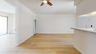 Located at 25004 Frampton Ave in the Harbor Gateway neighborhood of Los Angeles, this single-floor, one-bedroom, one-bathroom unit offers a well-organized layout that makes efficient use of its compact footprint. Light-toned hardwood-style flooring runs continuously throughout, lending a cohesive, clean aesthetic to the entire space.

The combined kitchen and living area forms the heart of the unit. The kitchen features white cabinetry, granite-patterned countertops, a built-in range, and a peninsula with a breakfast bar that opens toward the living area. An overhead range hood and vertical blind-covered window provide both functionality and natural light. The living area is generously proportioned relative to the overall unit size, with a ceiling fan overhead, wall-mounted heating units, and a pass-through window connecting back to the kitchen, enhancing the open feel.

The bedroom is a well-sized, quiet retreat with the same wood-style flooring, neutral white walls, and ample room for standard furnishings. The bathroom includes a tub and shower combination enclosed by frosted sliding glass doors with brushed nickel hardware, complemented by wood-style flooring and white tile finishes. Overall, the unit presents a bright, clean, and efficiently designed living space.