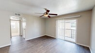 Located in Seabrook, Texas, this 2-bedroom, 1-bathroom residence offers a functional and comfortable single-floor layout. The living room is an open, welcoming space featuring rich hardwood-style flooring, a ceiling fan with light fixture, and a sliding glass door that opens to a private balcony overlooking the surrounding community — bringing in natural light and a sense of openness. The front entry leads directly into the living area, which connects seamlessly to the galley-style kitchen. The kitchen is well-appointed with gray cabinetry, light countertops, a tile backsplash, stainless appliances including a refrigerator and electric range, and hardwood-style flooring that continues the cohesive aesthetic. Both bedrooms are carpeted for comfort and each features a ceiling fan. The primary bedroom is generously sized, while the second bedroom includes a window with natural outdoor views. Four closets throughout the unit provide ample storage. The bathroom is clean and functional, featuring a full tub-shower combo with tiled surround, hardwood-style flooring, and a vanity with countertop. A hallway connects the private areas of the home. The textured ceilings and neutral wall tones throughout create a consistent, move-in-ready atmosphere.