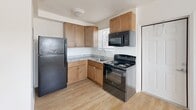 Located in Homestead, FL, this compact and efficiently designed one-bedroom, one-bathroom unit offers a functional layout across a single floor. Light wood-style flooring runs throughout the space, creating a clean and cohesive aesthetic that brightens each room.

The combined kitchen and living area forms the heart of the unit. The kitchen is outfitted with warm-toned wood cabinetry, granite-style countertops, and a full suite of black appliances including a refrigerator, electric range, and over-the-range microwave. A window above the sink allows natural light to filter in. The adjacent living area provides an open, flexible space that flows naturally from the kitchen.

The bedroom is a comfortable, well-proportioned room featuring a ceiling fan with light fixture, a textured ceiling, and a window dressed with horizontal blinds that invite natural light. A dedicated closet provides convenient storage. The room also features a wall-mounted air conditioning unit for individual climate control.

The bathroom is finished with crisp white square tile lining the tub and shower surround, maintaining a clean and simple aesthetic consistent with the rest of the unit.

Overall, the space presents a straightforward, functional design with neutral tones, ample natural light, and essential amenities — well-suited for those seeking a practical and easy-to-maintain living space in Homestead, FL.