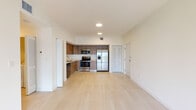 Located at 502 NW 207th St in Miami Gardens, FL, this single-floor unit presents a contemporary design with a bright, open-concept layout. The interior is finished with a neutral palette of crisp white walls and light-toned flooring that carries throughout most of the space, creating a cohesive and airy atmosphere.

The kitchen is well-appointed with warm wood-grain cabinetry extending to the upper walls, white quartz-style countertops, and a full suite of stainless steel appliances, including a side-by-side refrigerator with ice and water dispenser, an electric range, over-the-range microwave, and dishwasher. A dedicated pantry with wire shelving provides ample storage adjacent to the kitchen area.

The open living area connects seamlessly to the kitchen, offering generous space and access to an outdoor area through a sliding glass door. A secondary wet bar or utility area with additional cabinetry, a sink, and a dishwasher is also present.

The bedroom features light wood-style flooring, a walk-in closet, a window with exterior views, and direct access to the bathroom. Both bathrooms are finished with wood-tone vanities, white countertops, large mirrors, and light tile flooring. One bathroom includes a walk-in tiled shower, while the other offers a tub-shower combination.