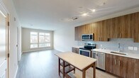 Located at 2803 Poag St in Alexandria, VA, this one-bedroom, one-bathroom unit offers a well-designed layout that maximizes its efficient footprint. The open-concept living and kitchen area features light-toned hardwood-style flooring, track lighting, and a clean, contemporary aesthetic throughout.

The kitchen is equipped with a full suite of stainless steel appliances, including a range, microwave, dishwasher, and refrigerator. Rich wood-grain cabinetry spans both the upper and lower sections of the kitchen, complemented by a light-colored countertop and a subtle tile backsplash. A kitchen island provides additional workspace and casual dining space.

The bedroom is carpeted and benefits from a large window that brings in natural light and offers views of the surrounding neighborhood. An adjacent walk-in closet features wire shelving on multiple levels, providing well-organized storage capacity.

The bathroom is finished with neutral tile flooring, a wood-grain vanity with a white countertop, a large mirror, and a full tub and shower combination enclosed by classic white subway tile. The overall design of the unit is cohesive, with a neutral color palette and modern fixtures that create a clean, functional living environment.