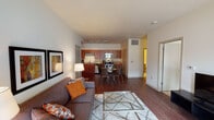This single-floor residence features a well-designed open-concept layout that seamlessly connects the living, dining, and kitchen areas. Rich hardwood flooring flows throughout the main living spaces, creating a warm and cohesive aesthetic.

The living room is bright and inviting, benefiting from natural light through a large window and a glass-panel exterior door. The space accommodates a comfortable seating arrangement alongside a glass coffee table and a media console.

The kitchen is well-appointed with warm-toned wood cabinetry extending to the upper walls, granite countertops, and a full suite of stainless steel appliances, including a range, microwave, dishwasher, and refrigerator. Track lighting overhead provides focused illumination throughout the kitchen and adjacent dining area, where a round glass table with seating for four is positioned.

The bedroom is a calm, carpeted retreat featuring a large window that admits natural light and outdoor views. Flanking nightstands with lamps and framed wall art complete the room's composed atmosphere.

The bathroom includes a wood-toned vanity with granite countertop, an undermount sink, and tile flooring. The unit also includes an attached garage with an automatic door opener, offering convenient enclosed parking and additional storage potential.