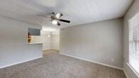 Located at 10881 Richmond Ave in Houston, TX, this single-floor, one-bedroom, one-bathroom unit offers a practical and comfortable layout. The open living room is finished with neutral-toned carpet and features a ceiling fan with integrated lighting, creating a bright and airy atmosphere. A wide window at the front entry fills the space with natural light, while a pass-through counter connects the living area to the galley-style kitchen. The kitchen is equipped with hardwood-style flooring, grey cabinetry, a black refrigerator, an electric range, and a tile backsplash accent, providing a functional cooking space. The bedroom is a comfortable size, also carpeted, and includes its own ceiling fan, a window with outdoor views, and direct access to both a dedicated walk-in closet and the full bathroom. The bathroom features a tiled shower-tub combination, a toilet, and a vanity with a marble-style countertop. Throughout the unit, soft grey walls and consistent finishes create a cohesive, clean aesthetic. A hallway connects the main living spaces, ensuring a logical and efficient flow throughout the home.