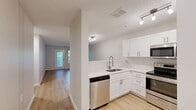Located at 100 Chamberlain Dr in Asheville, NC, this single-floor, 2-bedroom, 2-bathroom home offers a well-designed layout with a clean, modern aesthetic throughout. Light-toned hardwood-style flooring flows seamlessly across all rooms, creating a cohesive and bright atmosphere.

The kitchen is a standout feature, outfitted with crisp white shaker cabinetry, white quartz-style countertops, a stainless steel sink with a modern gooseneck faucet, and a full suite of stainless steel appliances including a range, over-the-range microwave, dishwasher, and refrigerator. Track lighting illuminates the space efficiently.

The living room is generously sized and filled with natural light from large windows and a glass door that opens directly onto a private patio, offering a seamless indoor-outdoor connection. Both bedrooms are well-proportioned, featuring ceiling fans, ample natural light, and access to closets — including a walk-in closet with wire shelving for organized storage. The primary bedroom is notably spacious.

Each bathroom is finished in a neutral palette with white vanities, quartz counters, tub-shower combinations with curved curtain rods, and stylish pendant or vanity lighting. An in-unit laundry area and a connecting hallway complete the thoughtfully arranged floor plan.