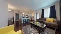 This well-appointed single-floor residence combines modern design with functional living spaces throughout. The kitchen serves as a central highlight, showcasing granite countertops, two-tone gray and white shaker cabinetry, a full suite of stainless steel appliances including a French door refrigerator, range, microwave, and dishwasher. A kitchen island with pendant lighting adds both counter space and visual appeal, while rich dark hardwood flooring and a subway tile backsplash complete the polished look. A window above the sink brings in natural light and greenery views.

The living room is bright and welcoming, featuring multiple windows dressed with navy curtains and blinds, dark hardwood floors, and access to an outdoor area via a glass door. The dining area, conveniently positioned nearby, accommodates a full dining set and includes an in-unit stacked washer and dryer for added convenience.

The bedrooms offer plush carpeting, ceiling fans, and generous natural light through double windows with blinds, providing a calm and restful atmosphere. The bathrooms are finished with granite-topped gray vanities, large mirrors, and glass-enclosed walk-in showers set over neutral tile flooring, delivering a clean, contemporary aesthetic throughout.