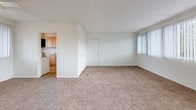 This single-story residence at 4874 E Los Coyotes Diagonal in Long Beach, California offers a practical and comfortable layout throughout. The living area is generously proportioned, featuring warm wall-to-wall carpeting, crisp white walls, and a large window dressed with vertical blinds that invite an abundance of natural light. A ceiling fan with a light fixture adds both comfort and functionality to the space.

The kitchen is well-appointed with warm-toned wood cabinetry, ample upper and lower storage, gray laminate countertops, and tile flooring. It includes a gas range, black dishwasher, over-range microwave, and a double basin sink positioned beneath a window, creating a bright and efficient workspace.

The bedrooms continue the carpeted, light-filled aesthetic, each featuring large windows with vertical blinds that frame views of surrounding greenery. Ceiling fans are present in select rooms, enhancing airflow and comfort.

The bathroom features tile flooring, a dark-finished vanity with a framed mirror, a soaking tub, and a window that provides natural ventilation and light.

Throughout the home, a consistent neutral color palette and textured ceilings provide a clean, cohesive feel. The floor plan, as revealed in the dollhouse view, presents a thoughtfully arranged single-level layout with well-defined living, sleeping, and kitchen zones.