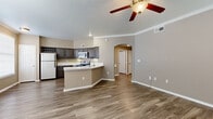 This single-story, three-bedroom, two-bathroom home in Round Rock, Texas offers a functional and comfortable layout throughout. The open-concept kitchen and living area serves as the heart of the home, featuring wood-look vinyl flooring, crown molding, and a ceiling fan with light fixture. The kitchen is equipped with dark cabinetry, white countertops, and stainless steel appliances including a range, microwave, and refrigerator, with an arched passageway connecting the space to the rest of the home. The living area is generously sized and bright, providing an inviting atmosphere. The spacious primary bedroom includes a ceiling fan, direct access to a walk-in closet with wire shelving, and an en-suite bathroom. The additional bedrooms are well-proportioned, each with ceiling fans and the same wood-look flooring. Both bathrooms are clean and functional, with one featuring a full soaking tub and shower combination, a vanity with dark cabinetry, and a large mirror. The dedicated laundry room houses a full-size washer and dryer. The attached garage offers additional storage and parking. Throughout the home, neutral warm-toned walls and consistent flooring create a cohesive and move-in-ready aesthetic.