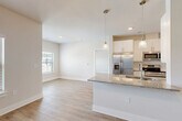 Located at 200 Travis Dr in McDonough, GA, this single-story home offers a thoughtfully designed open-concept layout that maximizes its comfortable footprint. Light wood-look flooring flows throughout the main living areas, complemented by crisp white walls and clean architectural lines that create a bright, welcoming ambiance.

The kitchen is a standout feature, boasting white shaker-style cabinetry, granite countertops, a tile backsplash, and a full suite of stainless steel appliances including a French door refrigerator, range, microwave, and dishwasher. A peninsula with pendant lighting connects the kitchen to the open dining and living areas, making it ideal for entertaining. The living room benefits from multiple windows and a ceiling fan, allowing natural light to pour in.

The bedroom offers plush carpeting, a ceiling fan, and a window with outdoor views. The bathroom features granite countertops and a soaking tub with full tile surround. Two closets provide generous storage. A dedicated laundry room with washer hookups, a utility room, den, and a patio round out the functional spaces, delivering a well-balanced and practical living environment.