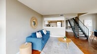 Located on East 6th Street in the heart of downtown Austin, Texas, this two-story, two-bedroom, two-bathroom residence offers a well-designed urban living experience across two floors. The main level features an open-plan living and dining area distinguished by striking polished concrete floors and expansive floor-to-ceiling windows that flood the space with natural light and frame dynamic views of the surrounding cityscape. A sleek metal staircase anchors the living area, serving as both a functional and architectural focal point. The pass-through kitchen is outfitted with white cabinetry, stainless steel appliances, and matching concrete flooring, offering convenient access to the main living space. Upstairs, the carpeted upper level is accessed via an open landing with metal railings and additional floor-to-ceiling windows. The generously sized primary bedroom features recessed lighting, soft carpeting, and a dedicated walk-in closet, creating a comfortable private retreat. A second bedroom and two full bathrooms — one with wood-look flooring and a shower/tub combination — complete the layout. Three closets throughout the residence provide ample storage. The warm neutral color palette, abundant natural light, and urban downtown location make this a distinctive two-level residence in one of Austin's most vibrant neighborhoods.