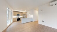 Located along the E Lake Sammamish Trail in Redmond, WA, this thoughtfully designed 2-bedroom, 2-bathroom residence offers a clean, modern aesthetic throughout its well-appointed single-floor layout. Light hardwood-style flooring flows seamlessly across every room, complementing the bright, neutral color palette that defines the space.

The open-concept kitchen and living area serves as the heart of the home. The kitchen features warm, light wood cabinetry with black hardware, a white subway tile backsplash, stainless steel appliances including a French door refrigerator, range, and microwave, as well as a central island with a white quartz countertop, undermount sink, and matte black faucet. Pendant lighting overhead adds a stylish finishing touch.

The living room is bathed in natural light, courtesy of expansive floor-to-ceiling windows and a glass door that opens to an outdoor balcony, offering views of mature evergreen trees and the surrounding neighborhood.

Both bedrooms are generously proportioned, each featuring large windows that frame lush, tree-lined outdoor scenery. The primary bedroom receives abundant natural light and provides a comfortable, serene retreat.

The bathrooms are finished in a clean, minimalist style, with one featuring a soaking tub surrounded by crisp white subway tile. A hallway connects all areas of the residence, ensuring a practical and efficient flow throughout.