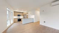 Located along the E Lake Sammamish Trail in Redmond, WA, this thoughtfully designed 2-bedroom, 2-bathroom residence offers a clean, modern aesthetic throughout its well-appointed single-floor layout. Light hardwood-style flooring flows seamlessly across every room, complementing the bright, neutral color palette that defines the space.

The open-concept kitchen and living area serves as the heart of the home. The kitchen features warm, light wood cabinetry with black hardware, a white subway tile backsplash, stainless steel appliances including a French door refrigerator, range, and microwave, as well as a central island with a white quartz countertop, undermount sink, and matte black faucet. Pendant lighting overhead adds a stylish finishing touch.

The living room is bathed in natural light, courtesy of expansive floor-to-ceiling windows and a glass door that opens to an outdoor balcony, offering views of mature evergreen trees and the surrounding neighborhood.

Both bedrooms are generously proportioned, each featuring large windows that frame lush, tree-lined outdoor scenery. The primary bedroom receives abundant natural light and provides a comfortable, serene retreat.

The bathrooms are finished in a clean, minimalist style, with one featuring a soaking tub surrounded by crisp white subway tile. A hallway connects all areas of the residence, ensuring a practical and efficient flow throughout.
