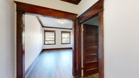 Located at 144 S Cannon St in downtown Spokane, WA, this one-bedroom, one-bathroom unit blends historic character with functional single-floor living. Throughout the main living areas, rich dark-stained wood trim, ornate door casings, and decorative ceiling moldings speak to classic early 20th-century craftsmanship. Hardwood floors run through the living room, dining room, and hallways, lending warmth and continuity to the space.

The dining room is a standout, featuring dual windows framed in deep mahogany-toned wood trim that flood the room with natural light and offer views of surrounding greenery. A vintage-style chandelier anchors the ceiling, adding an elegant period touch. The living room continues the hardwood flooring and detailed millwork, with a paneled entry door adding architectural interest.

The kitchen is compact and functional, equipped with a refrigerator, countertop space, and a window that brings in additional natural light. The bedroom is carpeted for comfort, finished with neutral tones, crown molding, and wall sconce lighting. Two windows provide ample daylight and outdoor views. The bathroom features a clean white tub-shower combination with hardwood flooring and white panel doors. Three hallways connect the rooms efficiently, completing this well-organized and character-rich unit.
