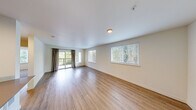 Located along the scenic West Lake Sammamish Parkway in Issaquah, WA, this well-appointed 2-bedroom, 2-bathroom residence offers a thoughtfully designed single-floor layout. The open living area features warm hardwood-style flooring, large windows, and a sliding glass door leading to a private balcony, filling the space with natural light and views of surrounding Pacific Northwest greenery. A hallway connects the living area to the rest of the home, providing a clear and functional flow throughout. The kitchen is outfitted with rich dark wood cabinetry, stainless steel appliances including a refrigerator, range, and microwave, ample counter space, and light wood-style flooring, creating a modern and efficient cooking environment. Both bedrooms are carpeted for comfort and equipped with ceiling fans. The spacious primary bedroom includes a generous closet, while the second bedroom also features a closet and a large window overlooking the tree-lined surroundings. Each of the two bathrooms is finished with wood-tone vanity cabinetry, a full tub-shower combination, light wood-style tile flooring, and a large mirror. A dedicated utility room completes the layout, adding practical storage and convenience to this well-rounded Issaquah residence.