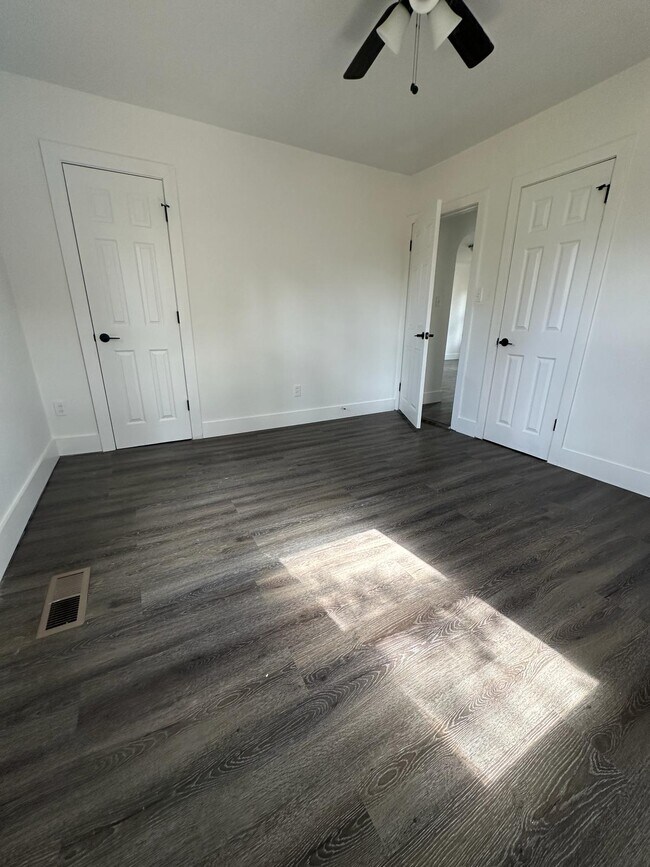 Habitación de invitados con pisos de madera oscura/estilo madera y ventilador de techo. - 1247 N Florissant Rd